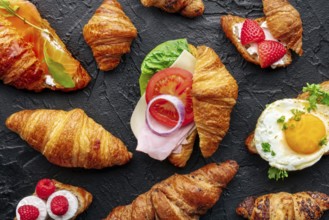 Croissant sandwich assortment. Many stuffed croissants, overhead flat lay shot on a black slate
