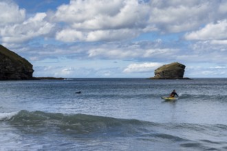 Portreath, United Kingdom, 4 September, lifeguard riding a wave on her emergency rescue board at
