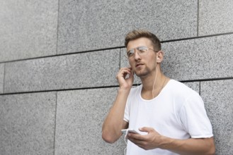 Earphones concept. People, technology, travel and tourism, man with earphones, smartphone on city