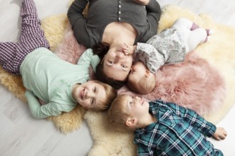 Top view of a beautiful young mother, her sweet little daughter and her two sons smiling at the