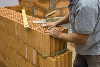 Anonymous construction worker on a building site erecting a brick wall. Brick wall of a solid house