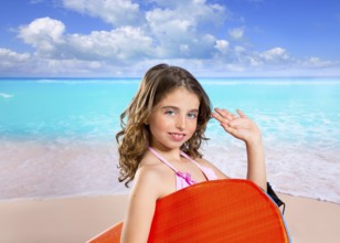 Children fashion surfer girl in tropical turquoise beach vacation with greeting hand