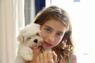 Kid girl with puppy white dog maltichon smiling