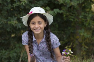 Girl with straw hat and bouquet of flowers