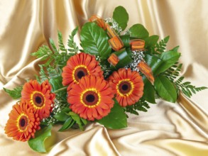 Bouquet of gerberas with green leaves over golden background