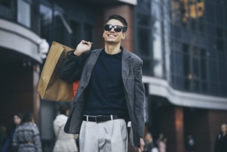 Serious cool guy with sunglasses and paper bags walking at street