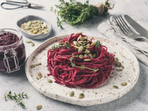 Beetroot pesto or hummus. Homemade beet pesto sauce in glass jar and fresh thyme on dark black