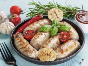 Chicken homemade sausages, sauces ketchup and vegetables and herbs on blue wooden background.