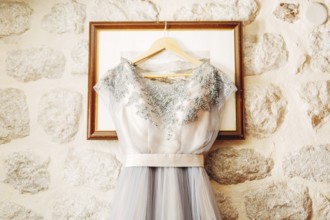 White wedding dress of the bride with patterns on a hanger on the picture frame.