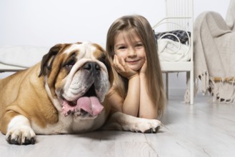 Two dreamy friends, a child and a dog, lie together in the room on the floor next to the bed and