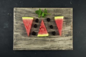 WATERMELON BLACKBERRY AND MINT ON THE BACKGROUND. THREE PIECES OF RIPE JUICY WATERMELON WITH RIPE