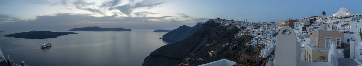 Cruise ship in the archipelago of Santorini, evening mood after sunset, white buildings at the edge