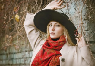 Beautiful young blond woman with long hair flying in the wind wearing hat in park