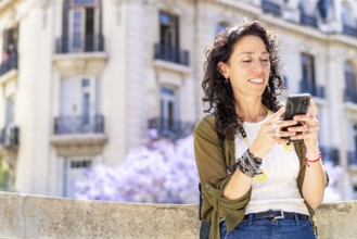 Smiling woman busy on her smartphone against a city backdrop