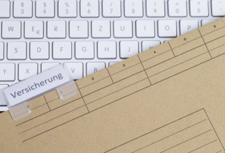 The photo shows a white keyboard with an insurance file folder