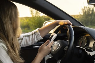 Womandriver using mobile phone paying for parking and navigating in the city while stopped on the