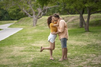 Couple kisses while walking through the park