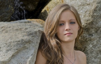 Headshot of pretty blue eyed, brunette girl against rocks