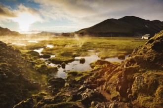 Above the source of thermal water steam rises. White nights in Iceland. Sunrise Park