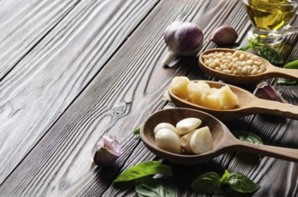 Closeup view at wooden spoons with food ingredients for genovese pesto sauce on kitchen table