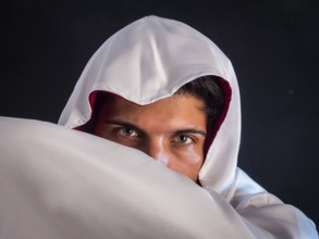 Close-up of handsome young man in old fashioned cloak on dark background