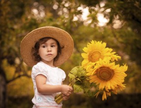 Little girl with sunflowers in a stetson on the garden
