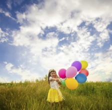 Happy child with colorful toy balloons outdoors