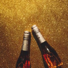 Christmas or New Year composition with bottles of rose champagne on golden shiny background, top