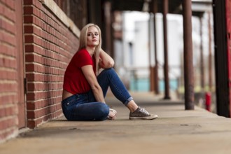 A beautiful blonde woman poses joyfully for the camera, showcasing her stylish spring clothing.