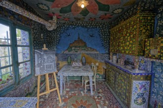 Colorfully decorated room with intricate mosaic artworks, paintings, a table, and chairs, Tourist
