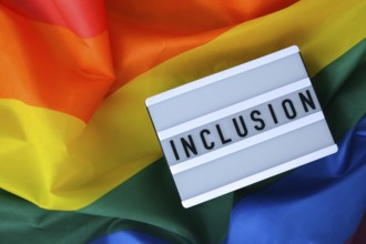 Rainbow flag with lightbox and text INCLUSION. Rainbow lgbtq flag made from silk material. Symbol