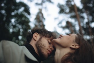 An intimate moment between a couple in a forest, exuding tenderness and tranquility