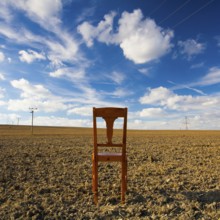 Old wooden chair on the empty field after harvest