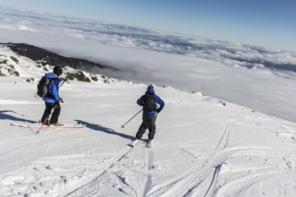 Two skiers are at the top of a peak of Vitosha mountain. They are participating in an freestyle