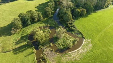 Aerial view of a beautiful green landscape with a small river flowing through. It is in the eastern