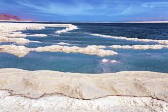 The evaporated salt forms bizarre patterns on the surface of the water. Cirrus clouds fly in the