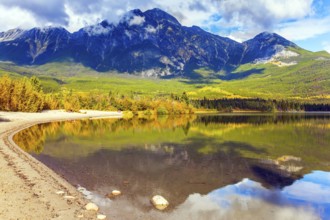 Rocky Mountains of Canada. Smooth water of the lake reflects Pyramid Mountain and lush cumulus