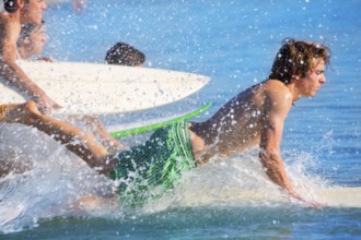 Boys teen surfers surfing running jumping on surfboards at the beach