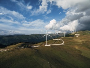 The prospect of a number of high industrial wind turbines on the hill, against the blue sky and