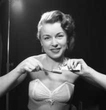 Brushing her teeth in the 1950s. A woman is pressing toothpaste onto her toothbrush. Sweden 1952.