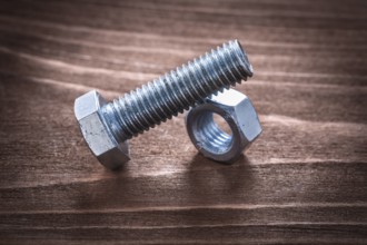 Threaded bolt and nut on vintage wooden board repairing concept