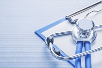 Stehoscope and clipboard on blue background medical concept