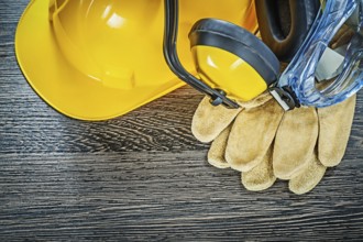 Protective gloves glasses earmuffs building helmet on wooden board