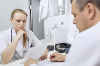 Doctor and nurse discussing analyses sitting at the table
