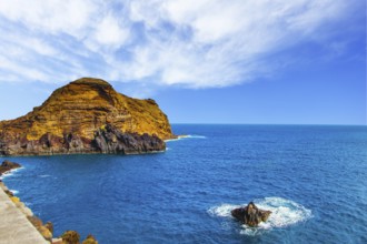 Calm bay with azure water. Rocks and stones off the shores of the volcanic island of Madeira. The