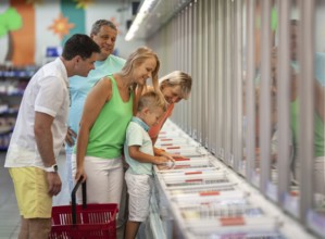 A boy, his parents and grandparents all together joyfully choose some goods in a store