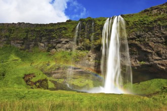Sunny day in July. Seljalandsfoss waterfall in Iceland. Large rainbow decorates a drop of water