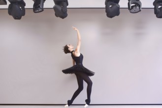 Young ballet dancer black swan practicing before performance in black tutu, classical dance studio,
