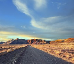 Argentine Patagonia. The gravel road between the endless pampas. The setting sun illuminates the