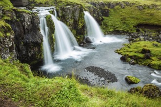Concept of exotic and extreme tourism. Cascading waterfall Kirkjoufellfoss at the foot of the